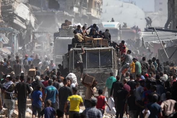 Un grupo de palestinos rodean camiones con ayuda humanitaria que llegaron este sábado a Jan Yunis (sur de Gaza), un día después de la entrada en vigor del acuerdo de alto el fuego.