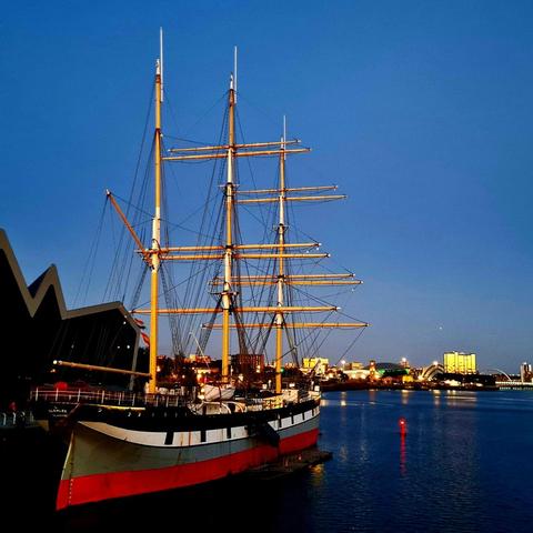 A tall ship lit up at night.