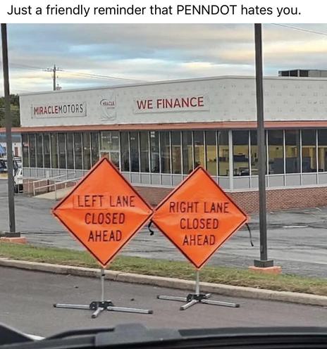 Two orange construction signs next to each other. One says “left lane closed ahead” and the other says “right lane closed ahead”.