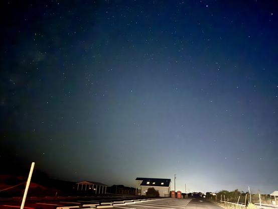 Night sky, starfield, cityglow on the horizon, bathhouse in foreground.