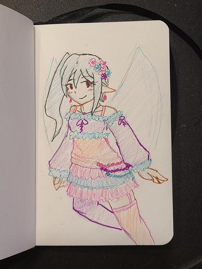 Drawing of a fairy on a small sketchbook, using colored markers and colored pencils. She has pointed ears and side ponytail, with a confident smile. She is wearing frilly pastel clothes in lavender, pink, blue, and orange, with a layered skirt and detached sleeves. She has flower decorations in her hair and colored beads at her hip. She is also wearing mismatched socks.