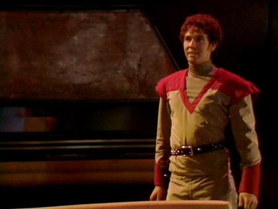 Claude Sonnet 4.0 describes the image as: "I can see a figure in what appears to be a futuristic or science fiction setting, wearing distinctive costume elements including red and tan/brown colored clothing with a cape-like garment. The character appears to be on what looks like a spaceship or futuristic interior set, with curved walls and technological elements visible in the background. The lighting creates a dramatic atmosphere typical of science fiction television productions from this era. The costume design suggests this is likely a main character, with the outfit having a somewhat militaristic or adventurous style that fits the space opera genre."

Blakes7Bot, version 3.9.33.