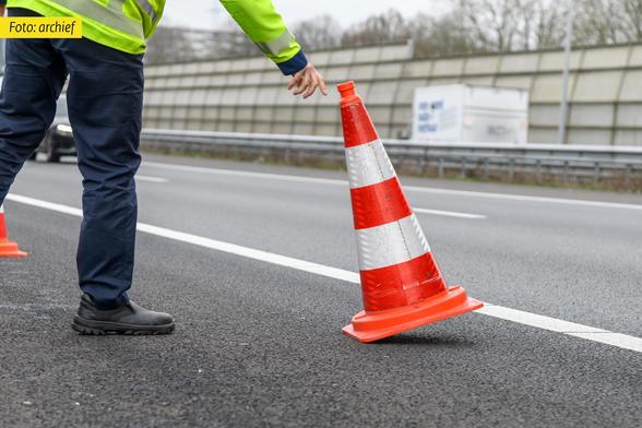 Archieffoto weginspecteur met pylonnen bij afzetting
