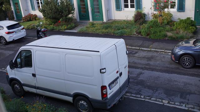 Weißer Kleintransporter steht auf dem Fußweg, während ggü auf der richtigen Fahrbahnseite (in Fahrtrichtung) eine Parklücke deutlich länger als jenes Fahrzeug frei ist.

Zum aussteigen muss der Fahrer durch den Vorgarten stapfen, Fußgänger müssen auf die Straße und PKW die die Sackgasse verlassen müssen auch eine nochmals schmalere Fahrbahn hinnehmen.

Nein, der Fußweg oder dessen Begrenzung ist nicht darauf ausgelegt solche Lasten zu überstehen, weshalb er auch reichlich kaputt ist.