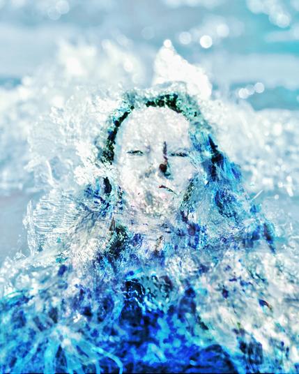 Color photo, light blue and turquoise tones, ice crystals in double exposure with the self-portrait of a woman who is barely distinguishable from the ice. Like an ice queen made of crystals, her eyes and mouth are vaguely recognizable, her long hair resembling icicles, cold and relentless without pity. Inspired by Peer Gynt, a scene in the Hall of the Mountain King, based on the text by Henrik Ibsen.