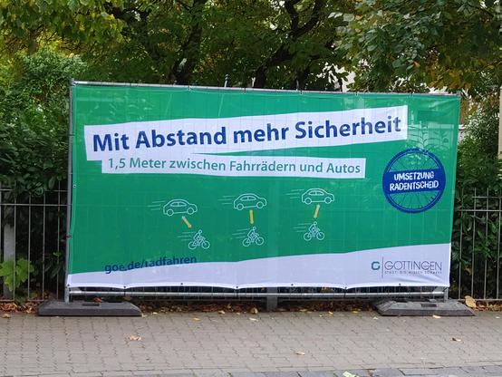 Plakat der Stadt Göttingen auf Baustellenabsperrgitter: "Mit Abstand mehr Sicherheit. 1,5 Meter Abstand zwischen Fahrrädern und Autos."
