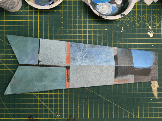 The bottom half of a sword blade with patches of metalic teal and blue.