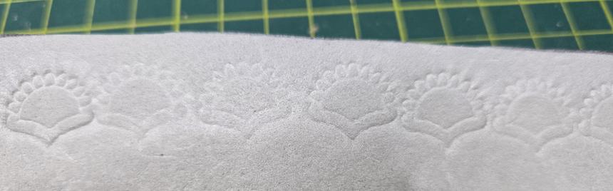 A sunrise design stamped into a horizontal line in EVA foam, with varrying distances from another and clarity.