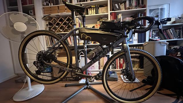 A gravel bicycle on a bike stand with a brand new set of Continental Terra Trail tires. The room is in shambles, the bike is dirty, but at least the tires are nice.