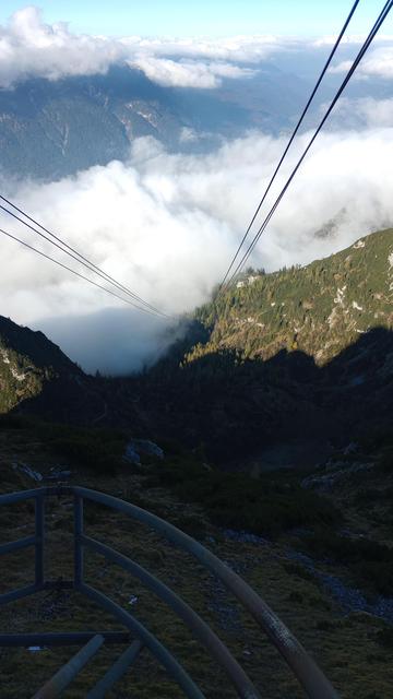 Blick entlang der Tragkabel der Seilbahn ins wolkenverhangene Tal