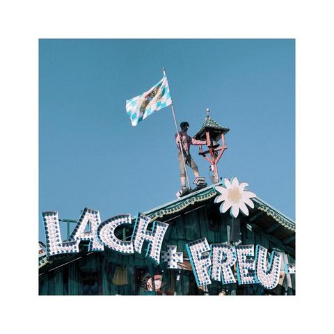 a detailed look at one of the facades of a oktoberfest attraction. parts of the colorful signage are visible. the logo says "smile and be happy". an edelweiss blossom sits in the middle. there's even a little figure holding a bavarian flag