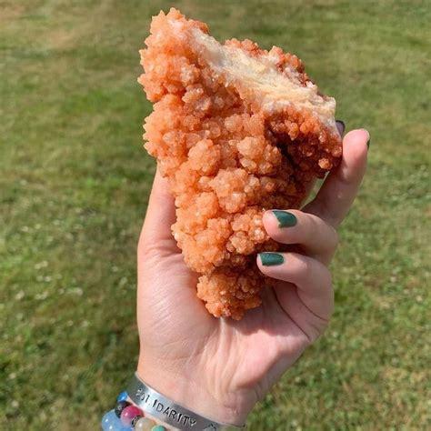 A crystal that looks like a massive chicken tender torn in half being held by a hand with green painted nails