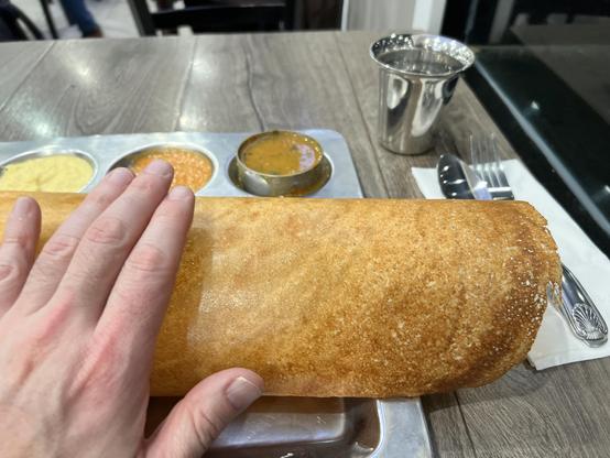 Hand hovering over a standard size dosa