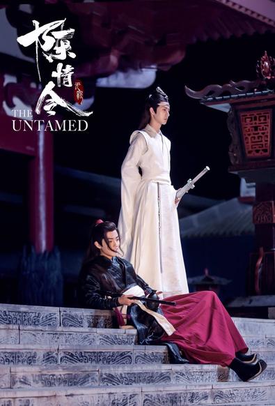 Wei Wuxian lounges on wide stone steps, leaning on his right elbow and holding his black dizi Chenqing in his right hand. Standing beside him at the top of the steps is Lan Wangji, his sword Bichen in its sheath held in his hand at his leg hip and his right hand tucked at the small of his back.