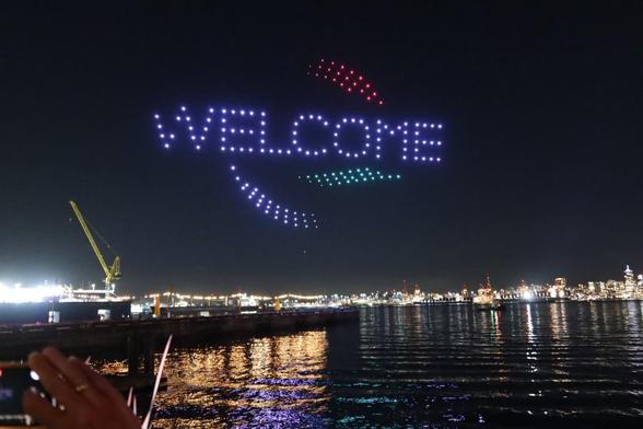 Drones with coloured lights in the shape of a "Welcome" sign.