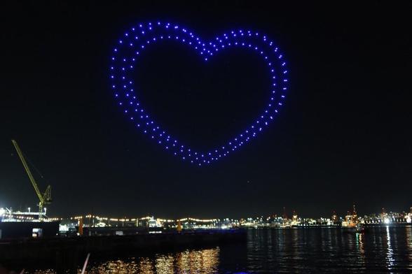 Drones forming a blue heart pattern in the sky.