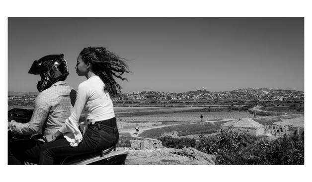 Deux personnes, un scooter et un seul casque. Des rizières et fours à brique en arrière plan.