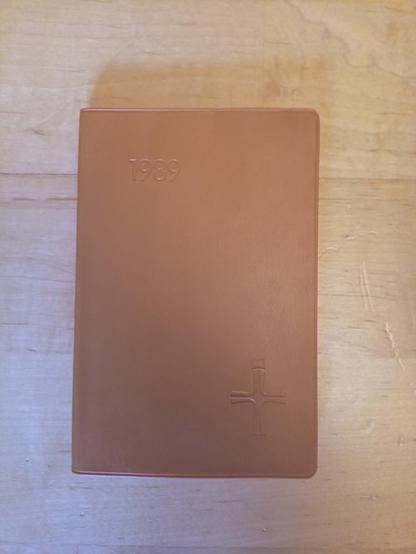 "Taschenkalender für Soldaten" für 1989, Format etwa 8,5 cm breit, 13 cm hoch. Farbe beige braun. Kunststoffeinband mit geprägtem Kreuz vorne unten rechts.
