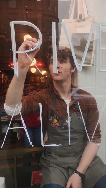 Close up of bookseller Jack starting to paint a new window design in the Edinburgh Bookshop