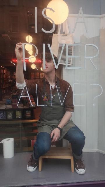 Longshot of bookseller Jack starting to paint a new window design in the Edinburgh Bookshop