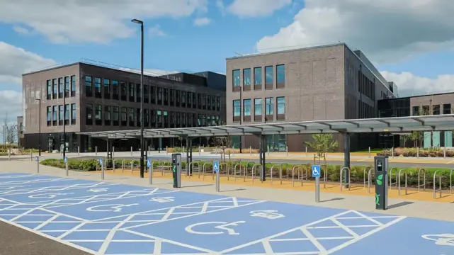 Front view of Pentre Awel building with EV charging bays.