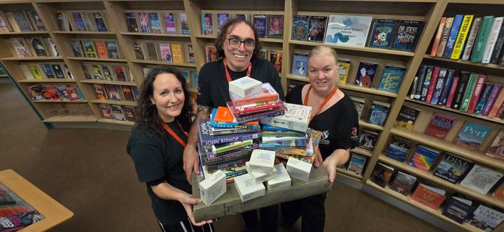 Three Swansea Central Library staff members packing books and preparing for relocation to Y Storfa.