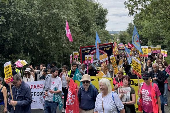 Hundreds of marchers walking through Epping Forest with banners.