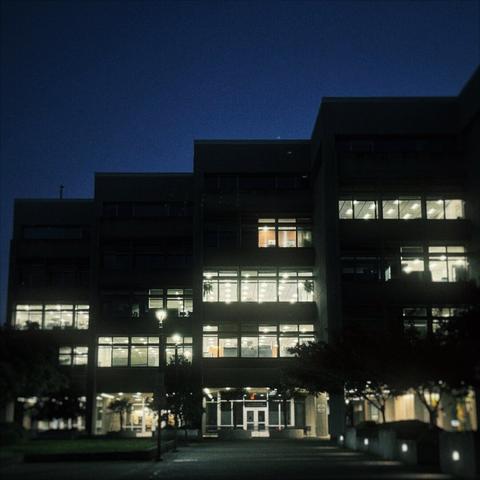 A large governmental building stacks itself in a horizontal, staggered array just before dawn on a clear morning.