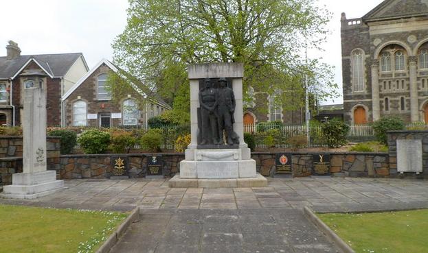 War memorials in the north‑east corner of People’s Park, Llanelli, featuring a statue of a coal miner and soldier with commemorative plaques.