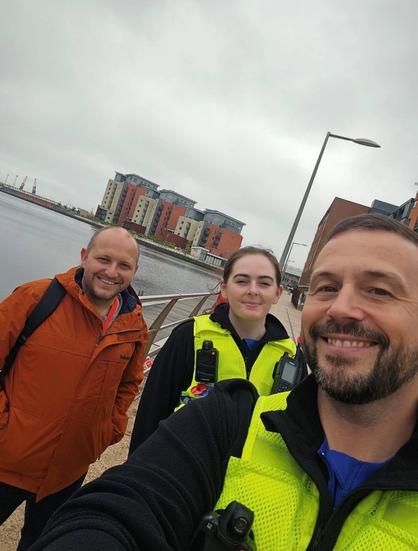 Two smiling police officers with councillor Sam Bennett at Swansea SA1.