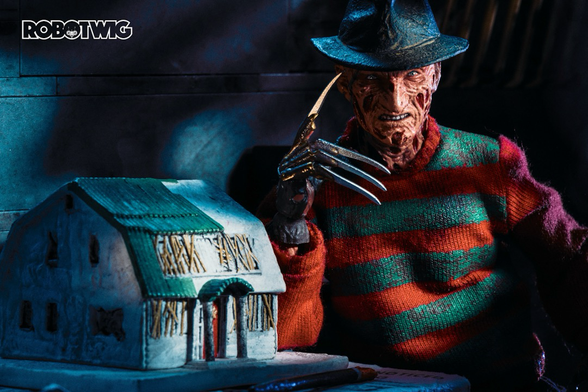 Freddy Krueger leans on a table next to a model of Nancy's old house.