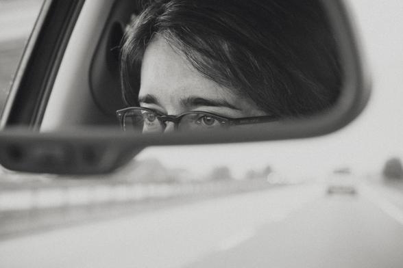 A woman’s eyes viewed in the rearview mirror as a cars heads down the highway.