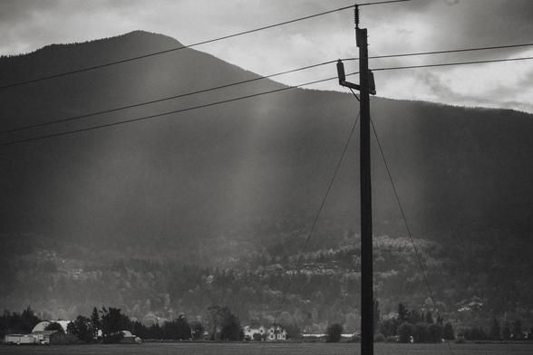 Sunbeams channel through clouds into a dark valley.