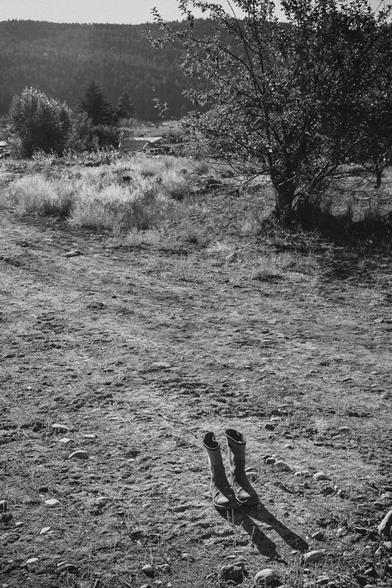 A pair of boots stand alone in a dirt clearing.