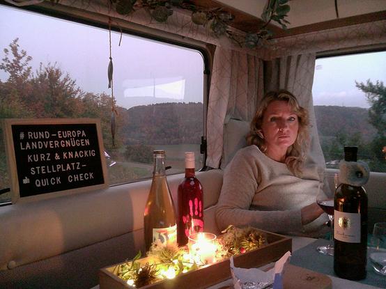 A woman is in a camper Witz candlelight and two bottles oft wine