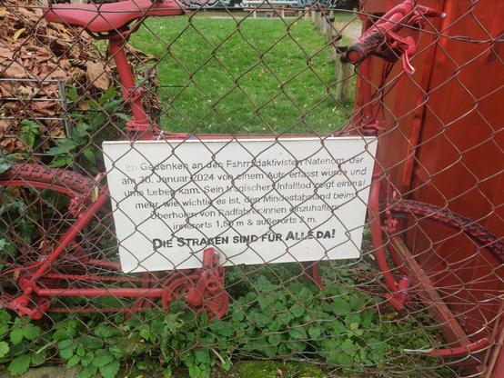 Rotes Fahrrad hinter einem Zaun, daran ein Schild das an Natenom erinnert.

"Im Gedenker an den Fahrradaktivisten Natenom der am 30. Januar 2024 von einem Auto erfasst wurde und ums Leben kam. Sein tragischer Unfalltod zeigt einmal mehr, wie wichtig es ist, den Mindestabstand beim Überholen von Radfahrern einzuhalten! innerorts 1,5m & außerorts 2m"