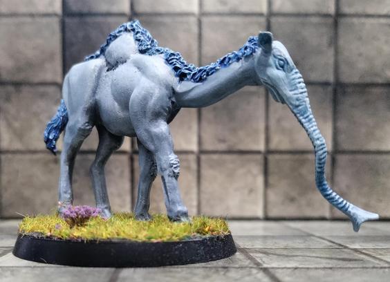 Blue furred camel body with an elephantine nose walking in short spring grass