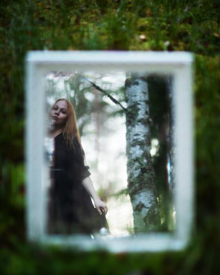 a reflection of a woman in forest in an antique mirror