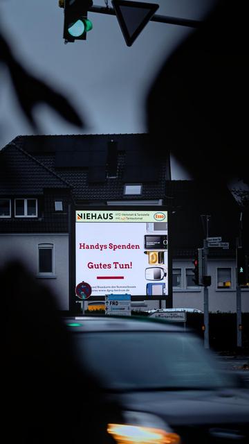 Foto einer Werbetafel an einer Kreuzung. Darauf ein Hinweis auf die Handysammelaktion der DPSG Beckum.