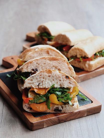 Several sandwiches filled with vegetables on wooden boards.
