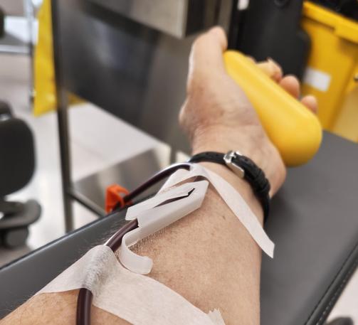 Thin tubing taped to my arm, connecting me to the plasma donation machine. I wear a watch & squeeze a yellow stress ball.