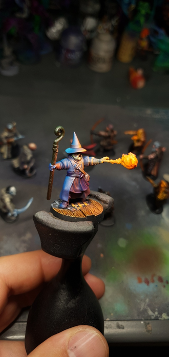 Gros plan sur le mage bleu, utilisant sa magie pour lancer une boule de feu. Sa tunique est bleu ,il porte un baton