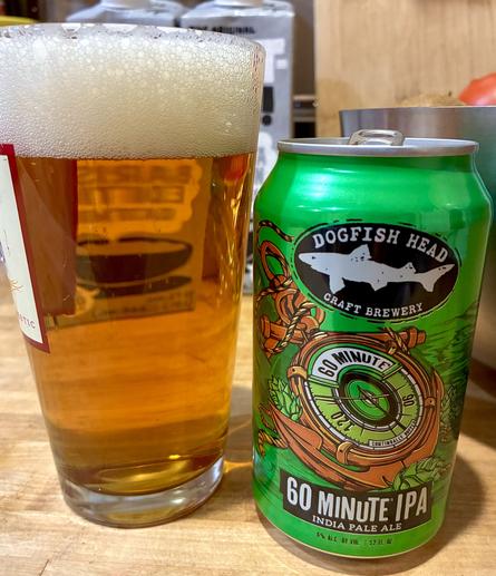 A glass of clear amber golden beer with its green can.