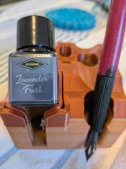 Diamine's Lavender Frost ink sits on a stand with a dip pen.