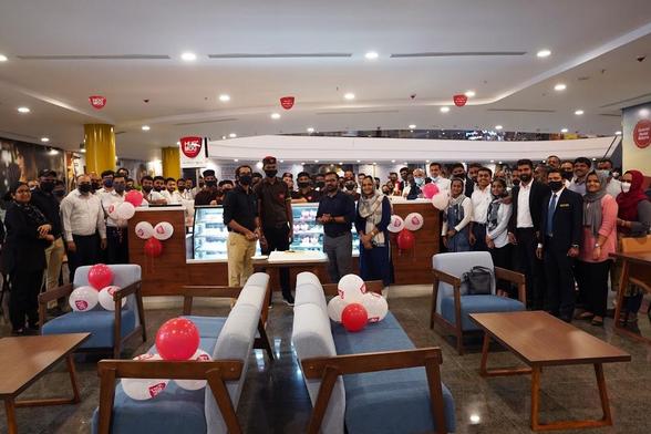 A group of people gathered inside a cafe, celebrating with balloons.