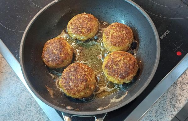Fünf Fischfrikadellen auf der Pfanne