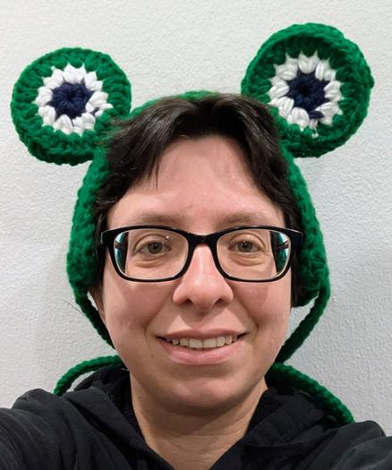 Person's head wearing a crochet headband with frog eyes