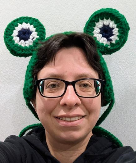 Person's head wearing a crochet headband with frog eyes