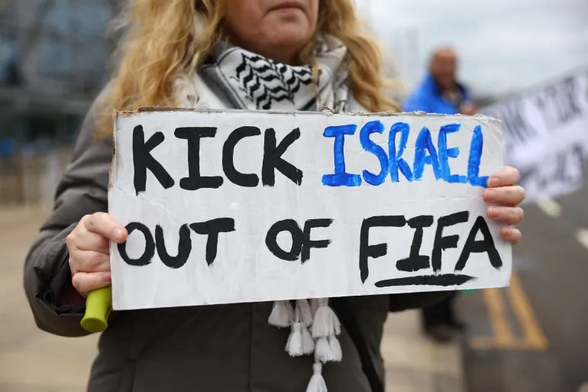 Supporter of Palestine holding a placard saying Kick Israel out of FIFA