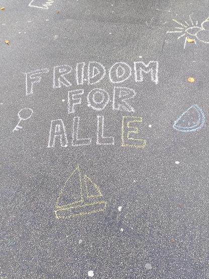 Kritt på asfalt. Teksten fridom for alle med biletar av ein nøkkel, ein vatnmelon og ein seglbåt.